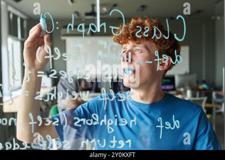 Schüler schreibt Computercode auf Glaswand Stockfoto