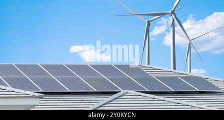 Solarpaneele auf dem Dach von Wohngebäuden und Windkraftanlagen erzeugen sauberen Strom für städtische Wohnhäuser. Nachhaltiger Strom für umweltfreundliche Stadtteile Stockfoto