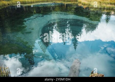 Kristallklarer, smaragdgrüner See mit unberührtem Wasser reflektiert den Himmel und umliegende Bäume und schafft eine ruhige natürliche Landschaft. Heiliger Frühling im Bergregion Stockfoto