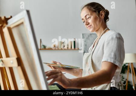 Ein Künstler mit Vitiligo malt fröhlich auf einer Leinwand in einem ruhigen Atelier. Stockfoto