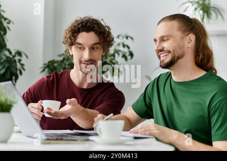 Ein fröhliches Paar teilt sich Kaffee und lächelt, während er an seinem Heimtisch arbeitet. Stockfoto