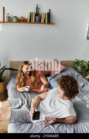 Im Bett kuschelt sich ein liebevolles Paar in ihrem gemütlichen Zuhause mit Lachen und Kaffee. Stockfoto