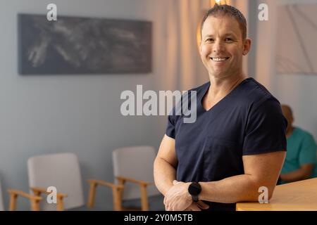 Lächelnder männlicher Arzt, medizinischer Mitarbeiter in der medizinischen Klinik, wartet auf Patienten, Kopierraum Stockfoto