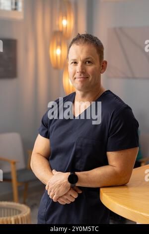 Männlicher Arzt oder medizinischer Mitarbeiter in der medizinischen Klinik mit Peelings, selbstbewusst am Zähler stehend Stockfoto