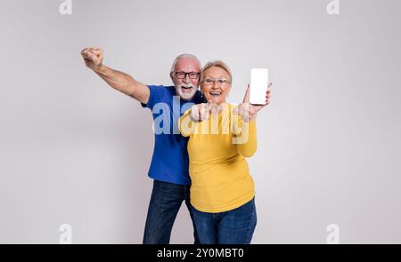 Ekstatisches Seniorenpaar schreiend und zeigt einen leeren Bildschirm des Smartphones vor weißem Hintergrund Stockfoto