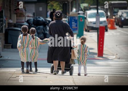 Ein Blick von hinten auf 3 bescheiden gekleidete orthodoxe jüdische Schwestern, die dasselbe Kleid tragen. In Brooklyn, New York. Stockfoto