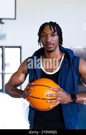 Basketball, afroamerikaner im Fitnessstudio, blauer ärmelloser Hoodie und Smartwatch Stockfoto