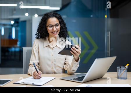 Glückliche und erfolgreiche hispanische Geschäftsfrau Finanzierin am Arbeitsplatz, Mitarbeiter lächeln verwendet Rechner, um Berichte zu vereinbaren und vorzubereiten, Büroangestellte hinter Papierarbeit. Stockfoto