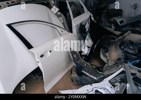 Tauschen Sie gebrauchte Autoersatzteile ein. Viele benutzte weiße Türen von Autos auf Schrottplatz. Schrotthaufen im Hof. Stapel von Türen für Ersatzteile. Stockfoto