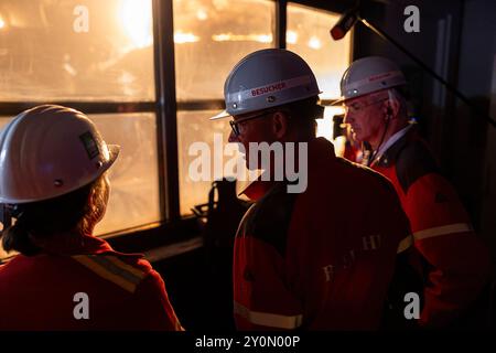 03. September 2024, Niedersachsen, Georgsmarienhütte: Friedrich Merz (M), Bundesvorsitzender der CDU, steht bei einem Besuch des Stahlwerks Georgsmarienhütte GmbH vor einem Fenster, hinter dem ein Gleichstrom-Lichtbogenofen in Betrieb ist und Schrott schmilzt. Foto: Michael Matthey/dpa Stockfoto