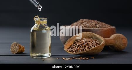 Haufen Leinsamen oder Leinsamen in Löffel oder Schüssel mit Glas Leinsamen Öl auf rustikalem Hintergrund. Leinsamen oder Leinöl Ballaststoffe Hintergrund Stockfoto