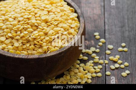 Rohe gelbe Linse in Schüssel auf hölzernem Hintergrund, (Linse culinaris) Stockfoto