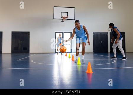 Dribbling Basketball um Kegel, weibliche Basketballspielerinnen trainieren im Fitnessstudio, Kopierraum Stockfoto