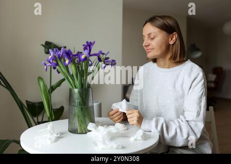 Saisonale Allergikerfrei. Junge Frau schnüffelt von Irisblumen, genießt den Geruch ohne laufende Nase, Jucken oder Husten saisonale Symptome in gemütlichem Zuhause. Gir Stockfoto