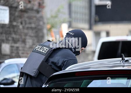 Wuppertal, Deutschland. September 2024. Ein maskierter Polizist mit Spezialausrüstung ist in der Nähe der Arbeitsagentur im Dienst. In Wuppertal ist ein großer Polizeieinsatz rund um die Arbeitsagentur im Gange. Ein Polizeisprecher sagte, dass mehr Truppen und mindestens ein Hubschrauber im Einsatz sind. Quelle: Roberto Pfeil/dpa/Alamy Live News Stockfoto