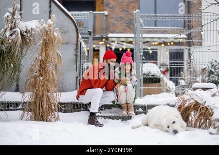 Ein junges Paar mit Hund auf der Veranda ihres Hauses im Winter Stockfoto