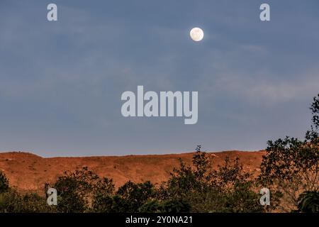 Der fast volle Halbmond erhebt sich über dem Berg Iguaque, in den östlichen Anden Zentral-Kolumbiens, an einem feenklaren Himmel bei Sonnenuntergang. Stockfoto