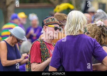 NEW ORLEANS, LA, USA – 10. FEBRUAR 2024: Die Menge trägt Mardi Gras-Kostüme und plaudert während des Karnevals auf einer Blockparty in Uptown Stockfoto