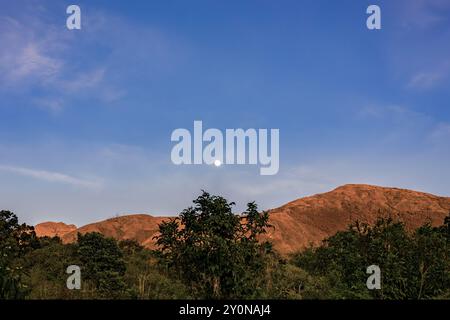 Der fast volle Halbmond erhebt sich über dem Berg Iguaque, in den östlichen Anden Zentral-Kolumbiens, an einem feenklaren Himmel bei Sonnenuntergang. Stockfoto