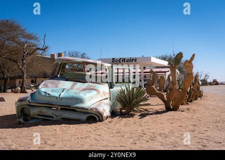 Ein alter verlassener Truck, halb in den Sand gesunken vor einem Schild für Solitaire in Namibia Stockfoto