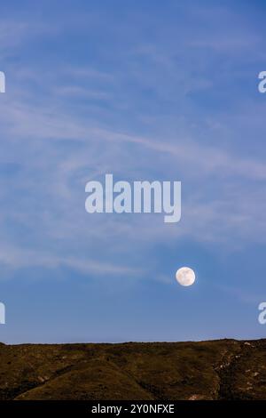 Der fast volle Halbmond erhebt sich über dem Berg Iguaque, in den östlichen Anden Zentral-Kolumbiens, an einem feenklaren Himmel bei Sonnenuntergang. Stockfoto