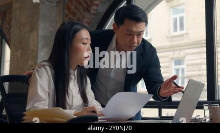 Asiatisch-koreanische Frau Büro Geschäftsfrau weibliches Mädchen Arbeit Papierkram Dokumente analysieren Chinesen Mann japanischer Geschäftsmann männlicher Kerl Geschäftsleiter kommen herein Stockfoto