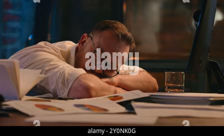 Müde müde erschöpft kaukasische Geschäftsmann Arbeitgeber schläft am Tisch auf Papier Schlaf Schlaflosigkeit Gesundheitsproblem chronische Erschöpfung spät Zeit Stockfoto