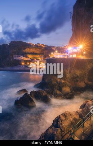 Der Pier von Ponta do Sol nach Sonnenuntergang mit Lichtern der Stadt auf Madeira, Portugal. Langzeitbelichtung, Atlantik Stockfoto