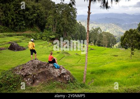 Touristen, Wanderer, Mutter und Sohn auf einem Felsen, umgeben von Reisfeldern, Terrassen und Wald in Tinimbayo in der Nähe von Rantepao in Tana Toraja, Sulawesi Stockfoto