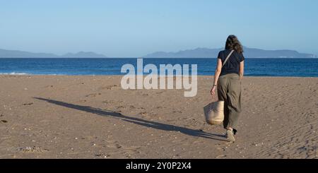 Blick auf eine weibliche Touristen, die in Richtung Meer am Kelvedon Beach, Haystack Rock, Eastern Tasmania, Australien läuft Stockfoto