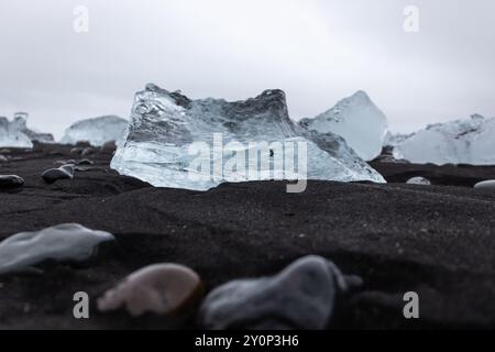 Transparenter Eisberg auf vulkanischem schwarzem Sand am Diamond Beach in Island, Nahaufnahme. Stockfoto