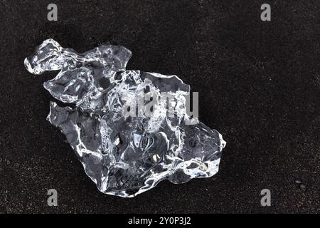 Einzelner transparenter Eisberg auf vulkanischem schwarzem Sand am Diamond Beach in Island, Blick von oben. Stockfoto