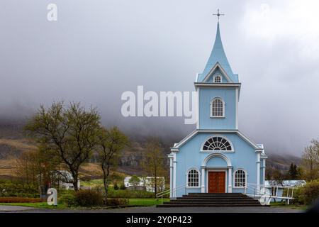 Die Blaue Kirche in Seydisfjordur (Seydisfjardarkirkja), Außenansicht der hellblauen Gebäudefassade, nebelige Berge im Hintergrund, Island. Stockfoto