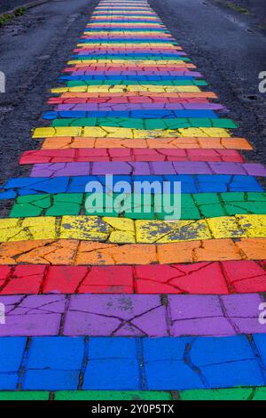 Rainbow Street (Regnbogagatan) in Seydisfjordur, Island, farbenfrohe Regenbogenstreifen, Straßenbelag aus nächster Nähe. Stockfoto