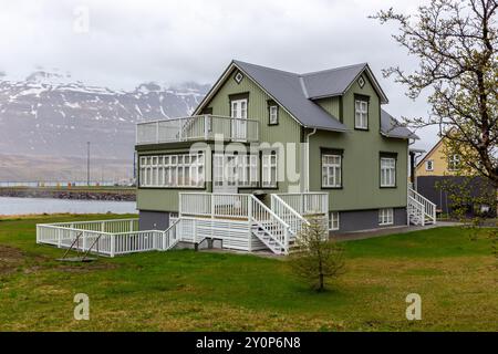 Traditionelles isländisches grünes Wohnhaus mit Giebeldach, weißen Fensterrahmen und Balkonen, verkleidet mit Wellblechen in Seydisfjordur Stockfoto