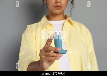 Frau mit Asthma-Inhalator auf grauem Hintergrund, Nahaufnahme Stockfoto
