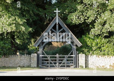 Hölzernes Lychentor und Steinmauer am Eingang zum Lyndhurst Kirchhof in der Nähe von Bolton's Bench, mit Bäumen im Hintergrund Stockfoto