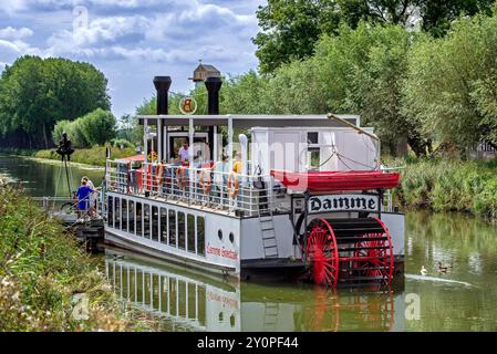 Touristen an Bord des Flussschiffes Lamme Goedzak auf dem Damse Vaart / Damme Kanal in der Stadt Damme im Sommer, Westflandern, Belgien Stockfoto