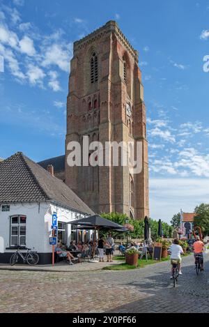 Touristen im Straßencafé und im gotischen Glockenturm der Marienkirche aus dem 13. Jahrhundert im Dorf Lissewege bei Brügge, Westflandern, Belgien Stockfoto