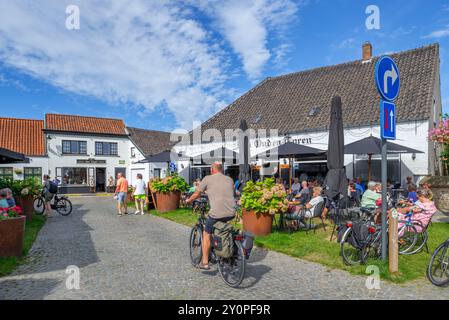 Touristen im Straßencafé des Pubs den Ouden Toren auf dem Marktplatz im Dorf Lissewege bei Brügge im Sommer, Westflandern, Belgien Stockfoto