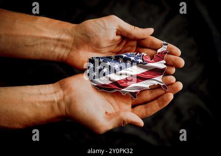 Männliche Hände, die die US-Flagge in Form der US-Karte halten. Bild für die Präsidentschaftswahlen 2024, wo die Zukunft Amerikas Stockfoto