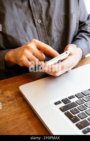 Geschäftsmann mit Smartphone und Laptop Stockfoto
