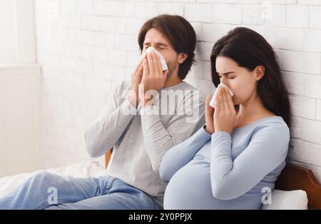 Schwangere paar Krankheitsgefühl, saß auf dem Bett und blasen Nasen Stockfoto