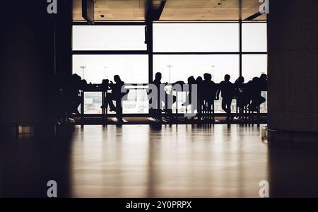 Silhouetten von Passagieren am Shanghai Pudong International Airport, die im Abflugbereich auf ihren Flug warten. Stockfoto