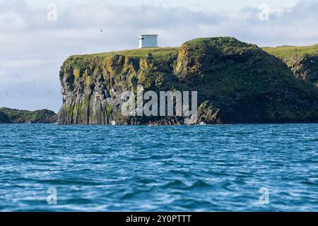 Küste mit Vogelklippe und Leuchtturm vom Wasser aus gesehen. Arnastapi, Snæfellsbær, Halbinsel Snæfellsnes, Westisland Stockfoto