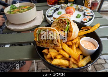 Essen Sie leckere Wraps mit Pommes frites in einem Restaurant mit Blick auf den Tisch Stockfoto