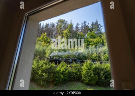 Ein von einer Dampflok gezogener Zug der Zittauer Schmalspurbahn fährt am Hotel Teufelsmühle in Oybin Landkreis Görlitz im Zittauer Gebirge in Sachsen vorbei. *** Ein von einer Dampflokomotive gezogener Zug auf der Schmalspurbahn Zittau passiert das Hotel Teufelsmühle in Oybin im Landkreis Görlitz im sächsischen Zittau-Gebirge Stockfoto