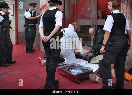 London, England, Großbritannien. September 2024. Spezialpolizisten verwenden Schneidausrüstung, um die Aktivisten aus ihrer Sperre zu befreien. Aktivisten blockieren den Haupteingang zu den Büros des APCO in The Strand in London, indem sie sich an einem Feuerlöschschloss befestigten, nachdem sie das Äußere des Gebäudes mit blutroter Farbe besprüht hatten. APCO werden von Elbit Systems beauftragt, Politiker in ihrem Namen zu unterstützen. Palästinensische Aktionäre ergreifen weiterhin direkte Maßnahmen gegen Unternehmen, die es dem israelischen Rüstungsunternehmen Elbit Systems ermöglichen, im Vereinigten Königreich tätig zu werden. Die pro-palästinensischen Aktivisten haben sich zur Ausrottung verpflichtet Stockfoto