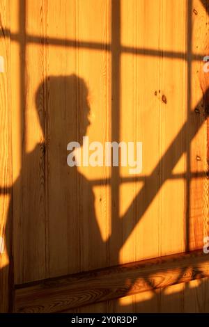 Silhouette einer Person auf Holzwand mit geometrischen Schatten Stockfoto