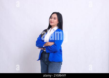 Der Charme einer hübschen jungen asiatischen Bürofrau, die einen blauen Anzug trägt, krumm nach rechts steht und mit überkreuzten Armen lächelt. Für corporat Stockfoto